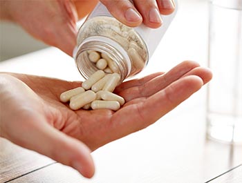 close up of man pouring pills from jar to hand PUGULFB